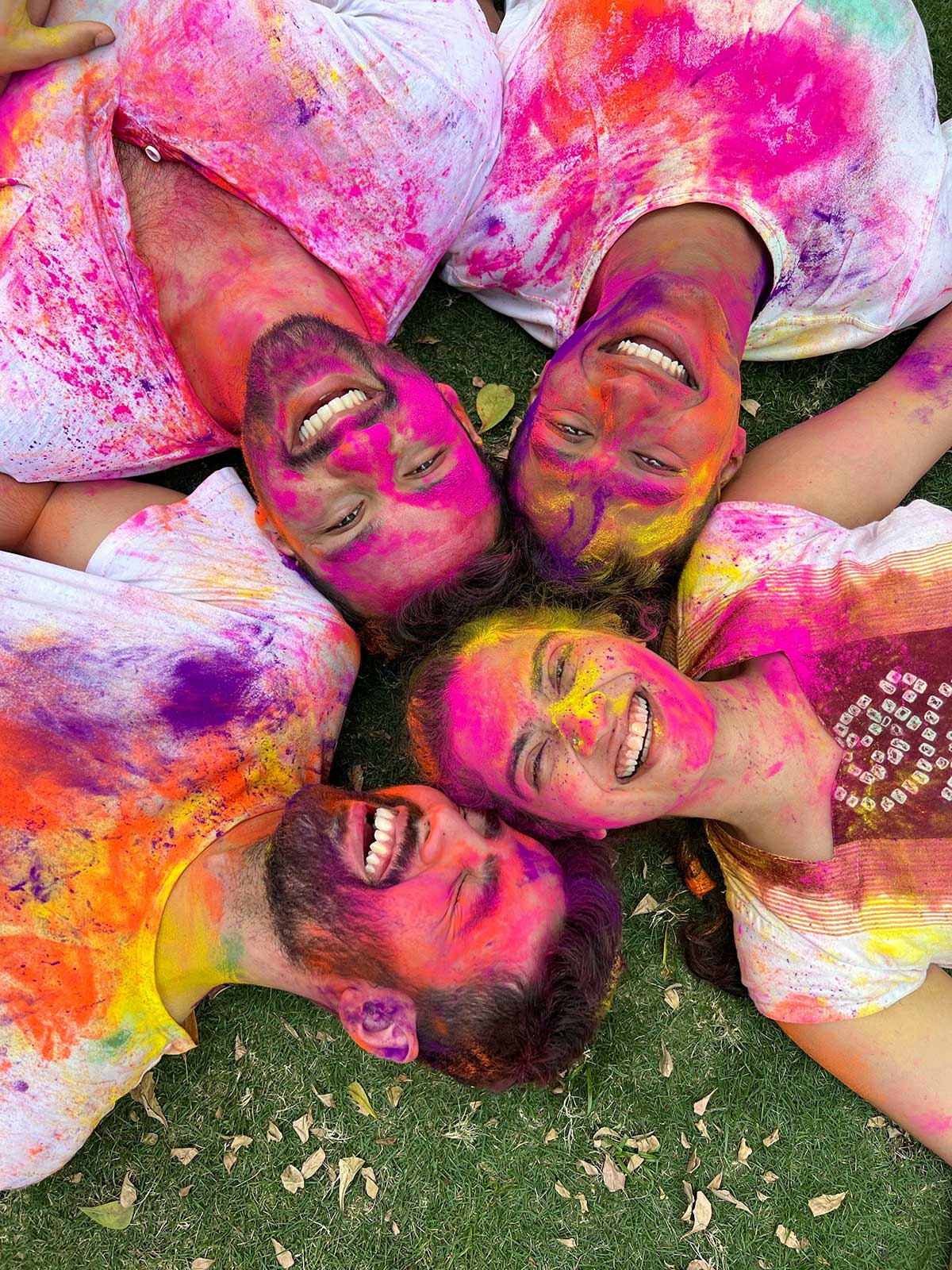 kreative events - glückliche Menschen voller Farbe liegen auf einer Wiese